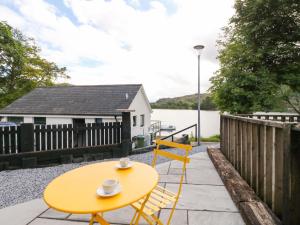 a yellow table and chairs on a patio next to the water at 1 Slatach in Glenfinnan
