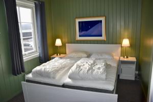 a bedroom with a bed with white sheets and a window at Nedre Stensgården in Røros