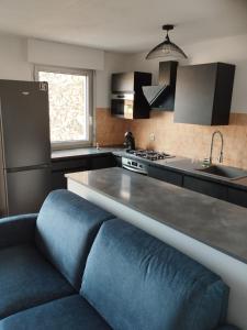 una cocina con un sofá azul frente a un mostrador en appartement 4 couchages renovés entièrement, en Cavaillon