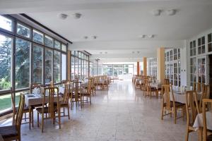Hotel Holiday Csopak في تشوباك: غرفة طعام مع طاولات وكراسي ونوافذ