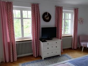 um quarto com uma televisão e uma cómoda com janelas em B&B Rosenliebe em Niedereschach