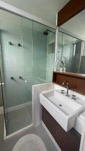 uma casa de banho com um lavatório e uma cabina de duche em vidro. em Amplo e iluminado apartamento na Gávea no Rio de Janeiro