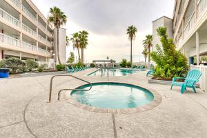 a pool in a courtyard with chairs and palm trees at Beachfront Corpus Christi Condo with Pool Access! in Corpus Christi