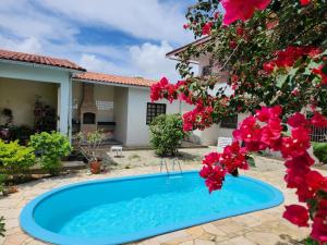 a swimming pool in front of a house with flowers at Hostel Atairú in Natal