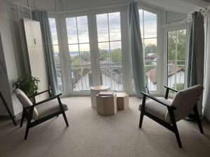 a living room with two chairs and large windows at Unglaublicher Seeblick I Sunset in Herrsching am Ammersee