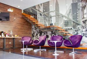 un hall avec des chaises violettes et un escalier dans l'établissement Aku Hotels, à Lima