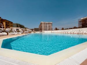 a large swimming pool with chairs and blue water at Demetra Seafront Apartment - Parking & Pool in Castel Volturno