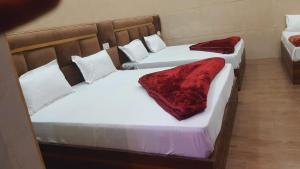 - 2 lits dans un dortoir doté de draps blancs et de couvertures rouges dans l'établissement Green leaf BnB, à Amritsar