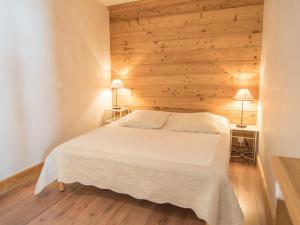 ティーニュにあるAppartement Tignes, 2 pièces, 4 personnes - FR-1-449-53の白いベッドと木製の壁が備わるベッドルーム1室が備わります。