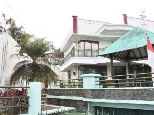 una casa blanca con una palmera delante de ella en Villa Hijau Bandungan en Bandungan