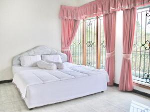Cama blanca en habitación con ventanas en Villa Hijau Bandungan en Bandungan