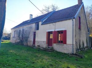 una pequeña casa blanca con puertas rojas en un patio en Lovely farm house, en Pouligny-Notre-Dame