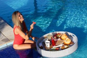 Eine Frau, die Essen neben einem Pool isst. in der Unterkunft Bali Hai Island Resort in Balian