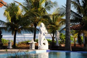 une statue à côté d'une piscine bordée de palmiers dans l'établissement Bali Hai Island Resort, à Balian