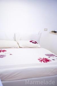 ein weißes Bett mit weißer Bettwäsche und roten Blumen darauf in der Unterkunft Marmelade in Zagarolo
