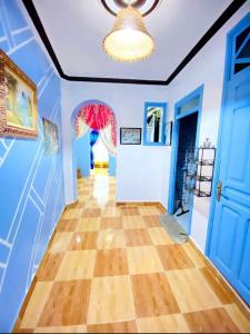 a hallway with blue walls and wooden floors and a chandelier at Casa Marisco in Chefchaouene