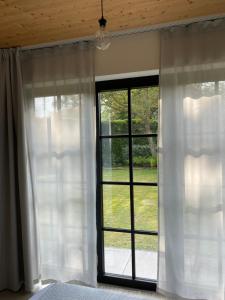 a bedroom with a large window with white curtains at de graslelie in Schoten