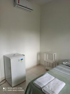 a room with a small refrigerator next to a bed at Pousada Luz da Vila Itaúnas in Itaúnas