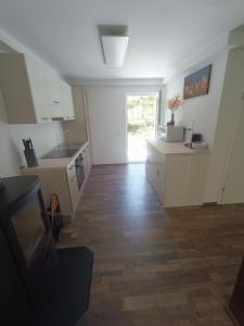 cocina con armarios blancos y suelo de madera en Riverside Guesthouse en Ig