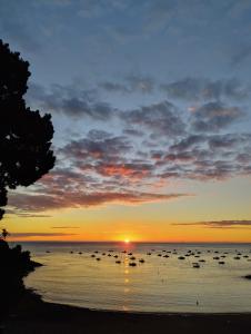 a sunset on the beach with boats in the water at Auberge de Jeunesse HI Cancale in Cancale