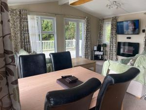 uma sala de estar com uma mesa de madeira e cadeiras em 3 Bedroom Lodge - Willows 24, Trecco Bay em Newton