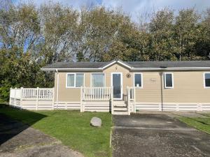 a small yellow house with a white fence at 3 Bedroom Lodge - Willows 24, Trecco Bay in Newton