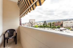 a chair sits on a balcony with a view of a city at Prime location Apartment with Three Bedroom in Tbilisi City