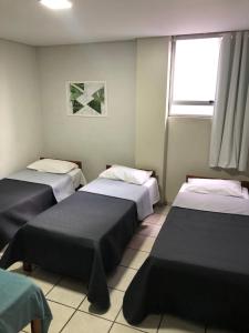 una habitación con tres camas y una ventana en Alameda Hotel Centro, en Garanhuns