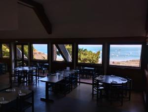 ein Restaurant mit Tischen und Stühlen und großen Fenstern in der Unterkunft Auberge de Jeunesse HI Cancale in Cancale