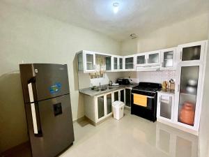 una cucina con armadietti bianchi e frigorifero nero di Balcón Skyline 2 a Jarabacoa