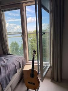 - une guitare assise à côté d'un lit avec une fenêtre dans l'établissement 32m2 asunto järven rannalta, à Kuopio