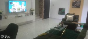 een woonkamer met 2 stoelen en een televisie bij George's property in Accra