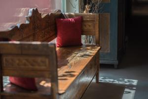 un banco de madera con una almohada roja en Settecentoalberi Agriturismo en Noventa di Piave