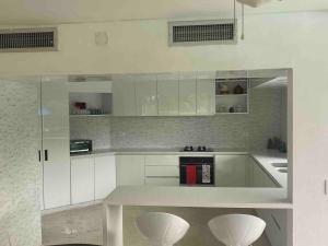 a white kitchen with white cabinets and white stools at Apartamento en el penon 5 alcobas 7 baños in Girardot