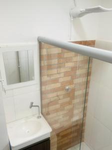 uma casa de banho com um lavatório e um chuveiro com um espelho. em NOVO APARTAMENTO Liz 3 em Porto Seguro