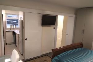 a bedroom with a bed and a tv on a wall at Leamington Park Studio with Parking in London