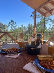 a wooden table with plates of food and glasses of orange juice at Glamping Town in Otinapa