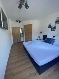 a bedroom with a large white bed and a flat screen tv at Apart Alpenherz in Schwendau