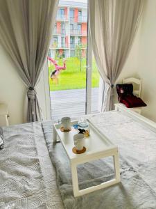 Un dormitorio con una cama blanca y una mesa. en Baltijos apartamentai, en Klaipėda