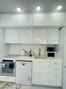 cocina blanca con armarios blancos y microondas en Baltijos apartamentai, en Klaipėda