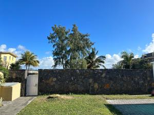 a retaining wall in a yard with palm trees at Villa De Alisha in Blue Bay
