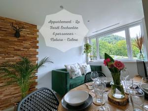 a dining room with a table and a green couch at La forêt Enchantée - Cozy Immo in Orschwiller