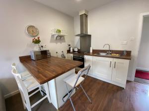 a kitchen with white cabinets and a wooden counter top at Irvinestown Fermanagh 2 Bedroom Apartment in Irvinestown