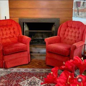 2 sillas rojas en la sala de estar con chimenea en No Centro de Gramado em condomínio encantador, en Gramado
