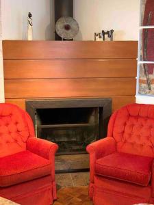 sala de estar con 2 sillas y chimenea en No Centro de Gramado em condomínio encantador, en Gramado