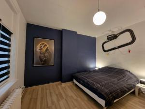 ein Schlafzimmer mit einem Bett und einer blauen Wand in der Unterkunft Le Garage in Lens