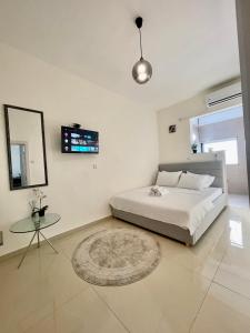 a white bedroom with a bed and a table at Estrela Mares Haifa in Haifa