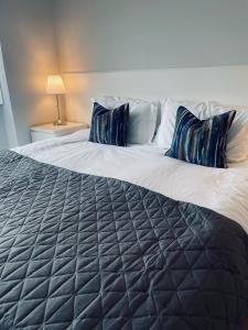 a large bed with blue pillows on top of it at Watts Lodge in Bicester