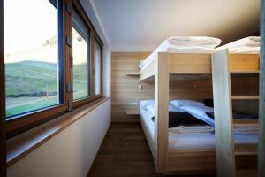 a small room with two bunk beds and a window at Berg Aparts - Top 6 - Faschina - mit Sauna & 2 Bädern in Fontanella
