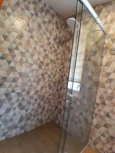baño con ducha y pared de mosaico en Casa Topázio no Container dos Cristais en Delfinópolis
